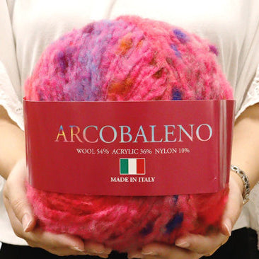 Ball of colorful yarn with 'Arcobaleno' label held by a person
