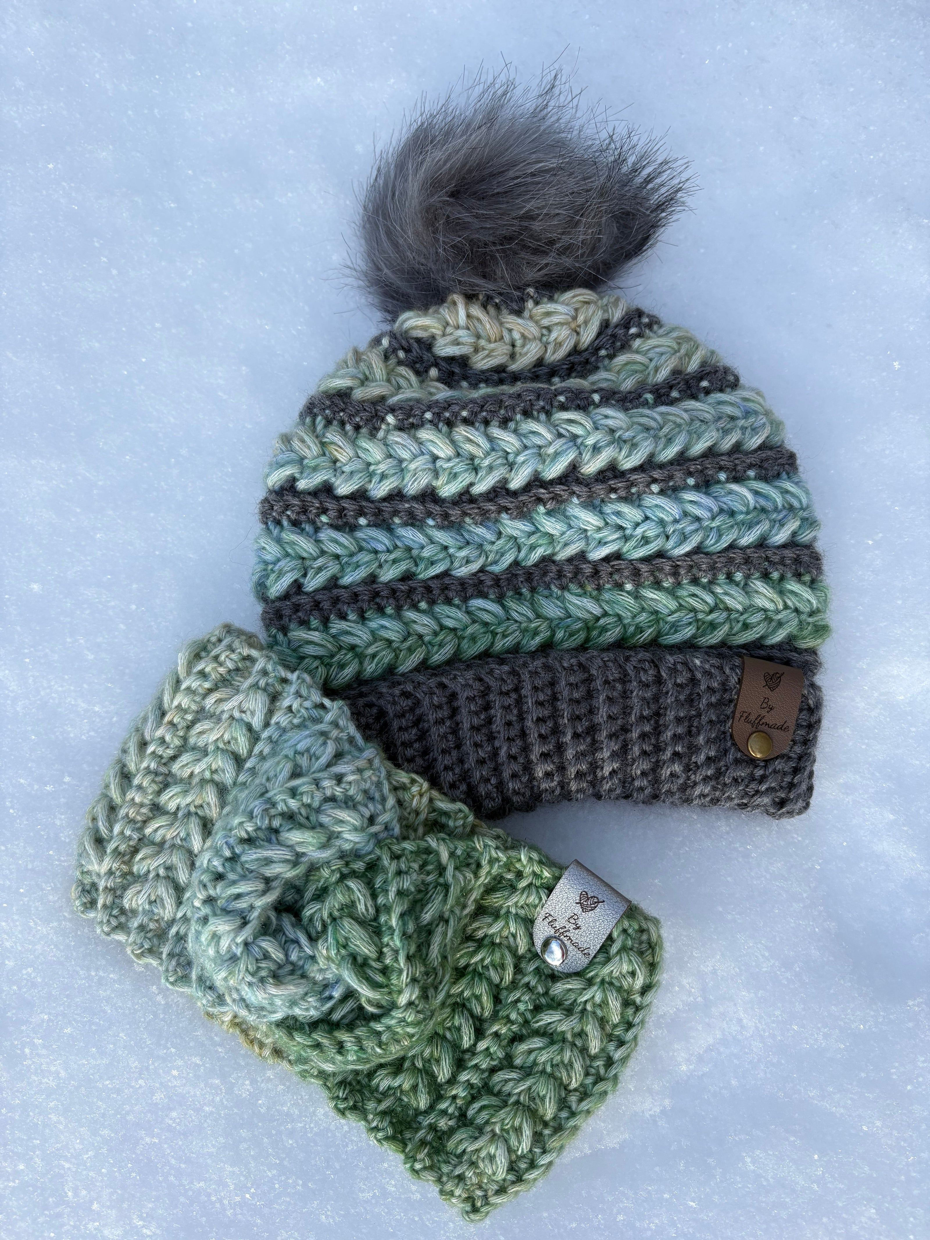 Crocheted green beanie with pom-pom and matching headband on snow