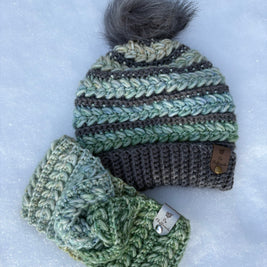 Crocheted green beanie with pom-pom and matching headband on snow