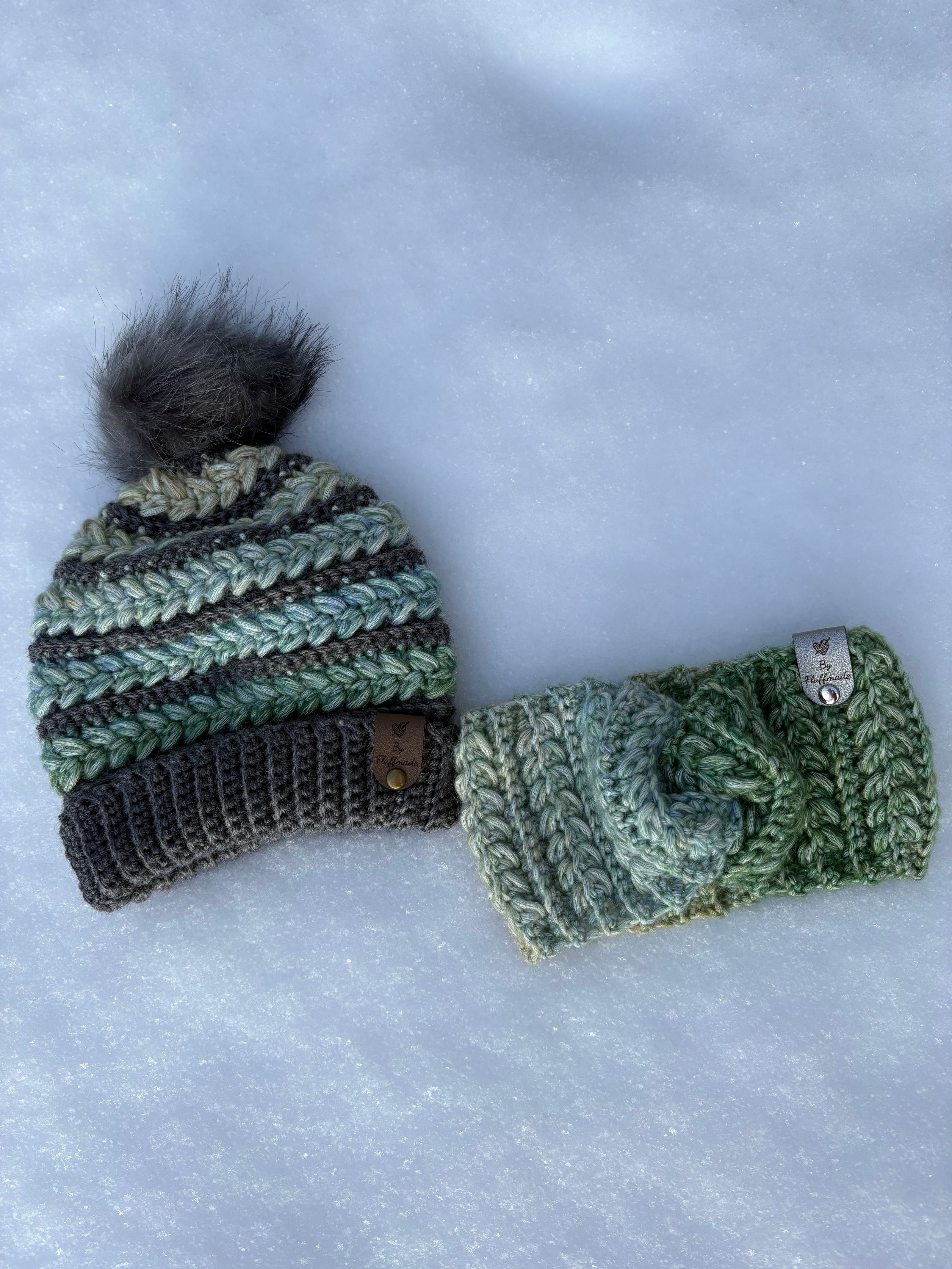 One crochet beanie with pom-pom and a headband on a snowy background in Pistachio Parfait.