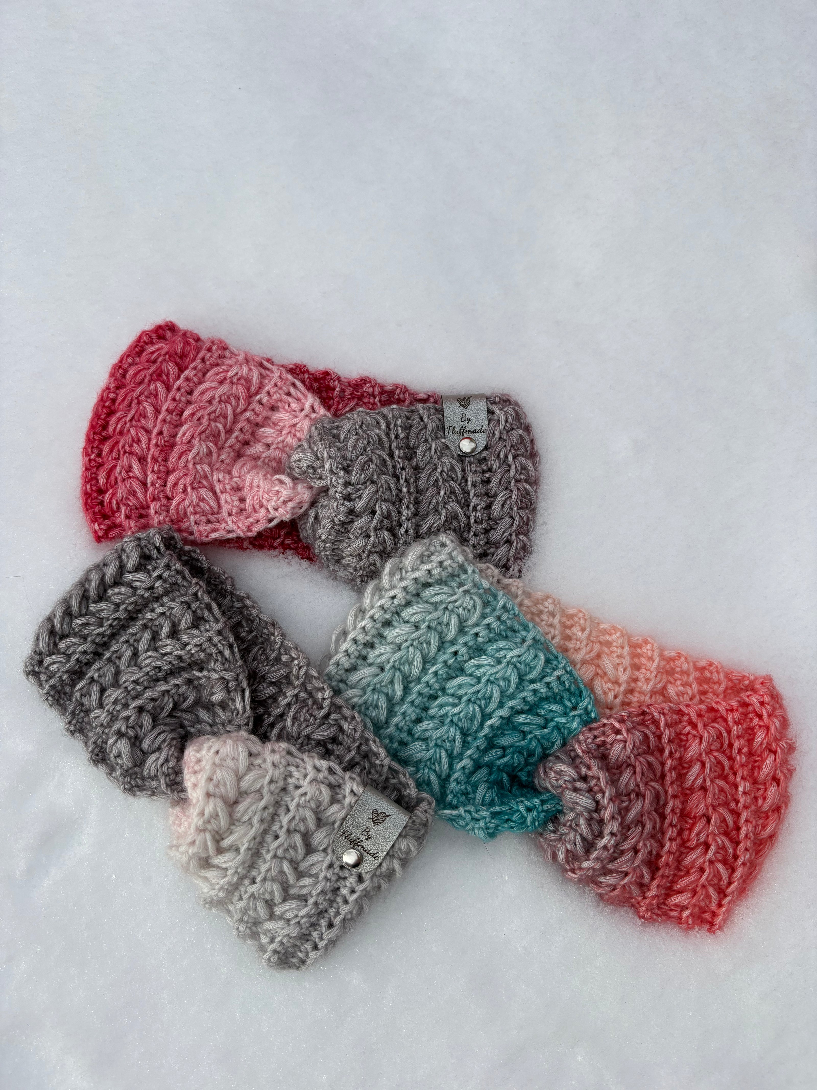 Crochet ear warmers in gradient colours displayed on snow – Fluffmade Solstice Collection handmade in Canada.
