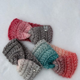 Crochet ear warmers in gradient colours displayed on snow – Fluffmade Solstice Collection handmade in Canada.