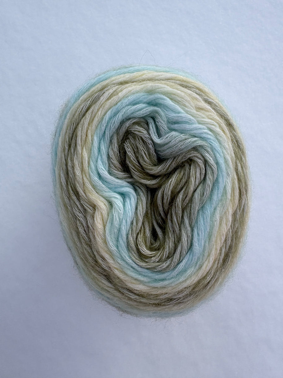 Multicolored green yarn skein on a light gray background