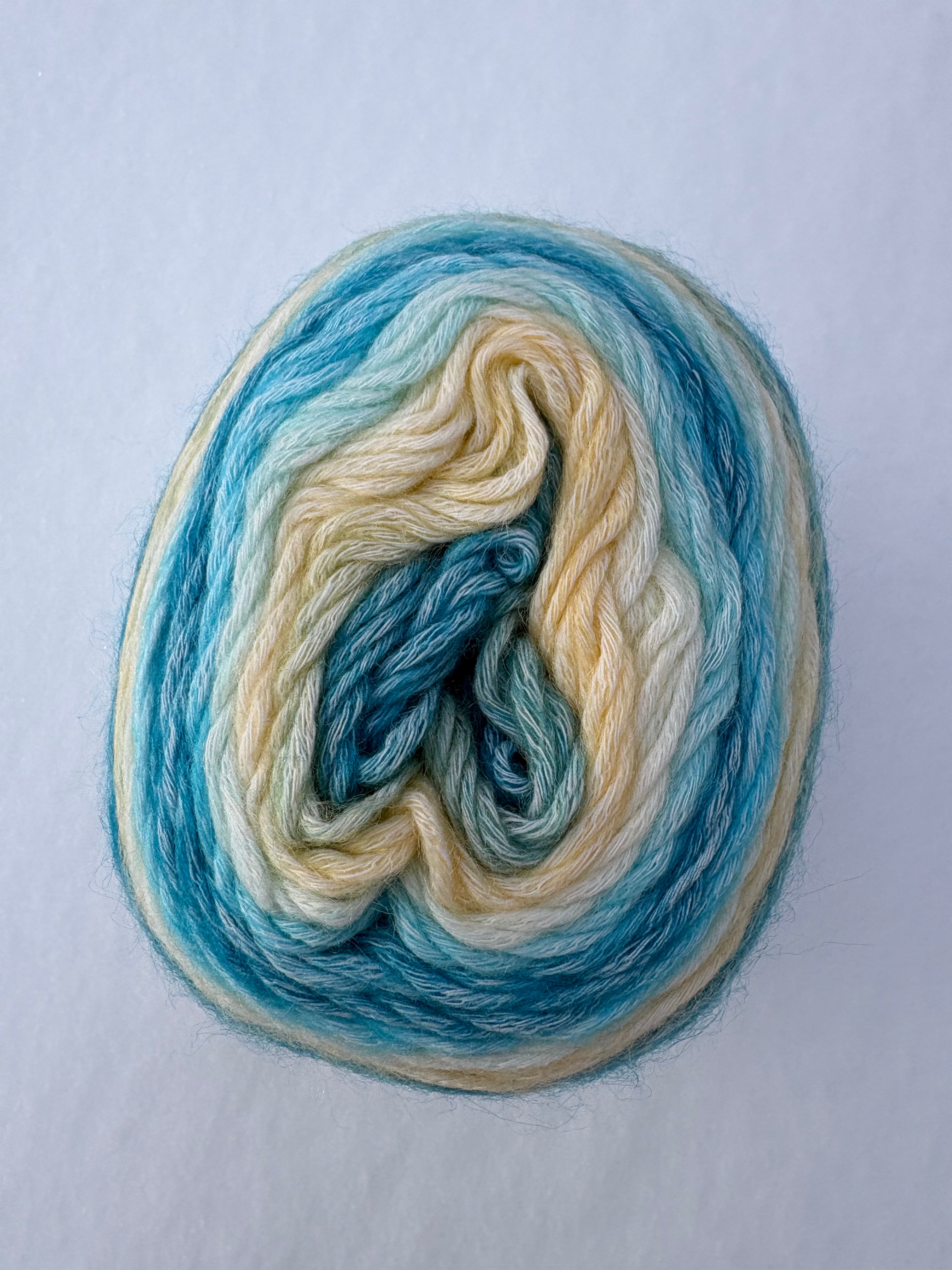 Wool yarn skein with blue and beige colors on a white background