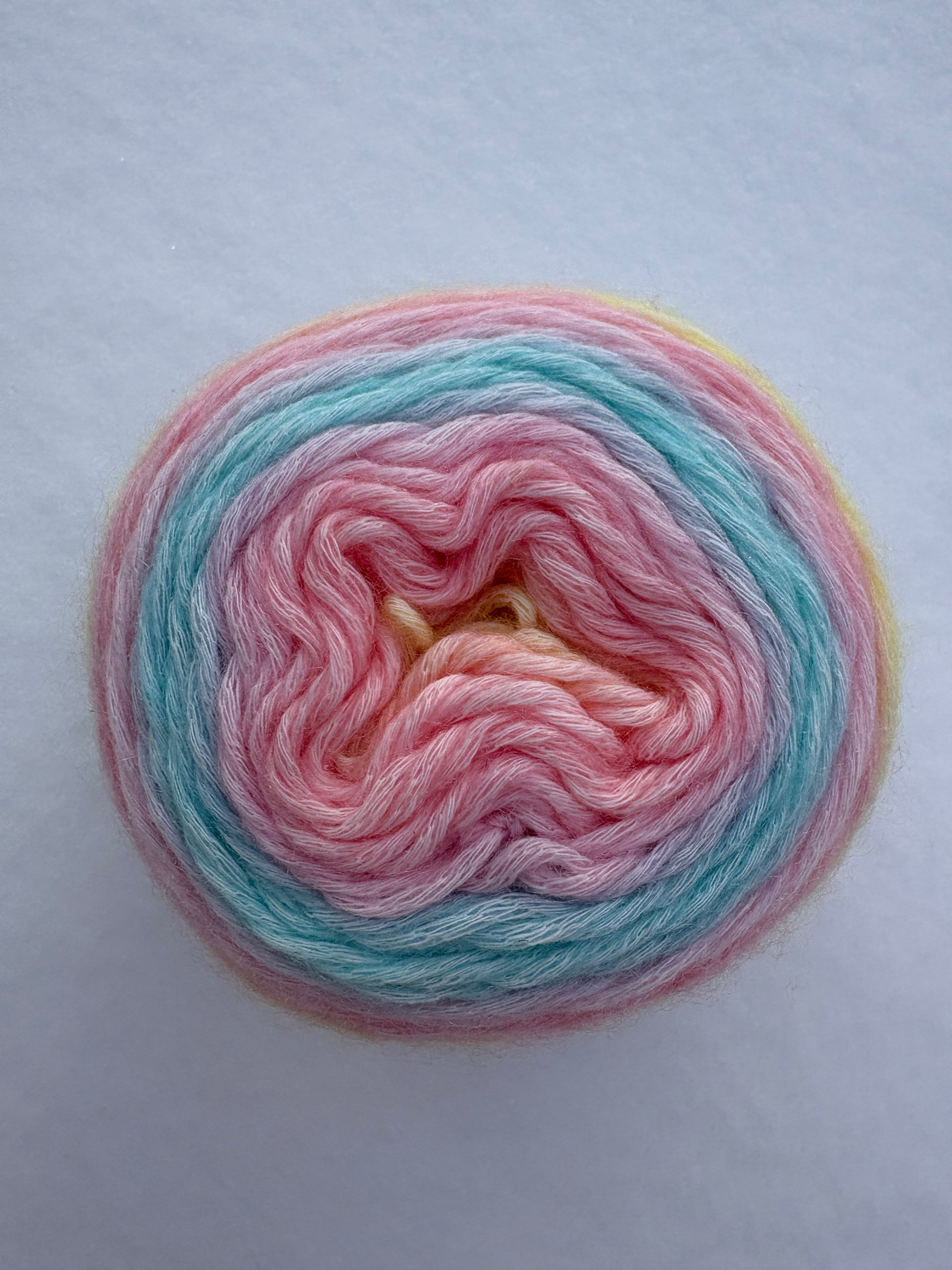 Multicolored pink, blue and yellow yarn skein on a light gray background