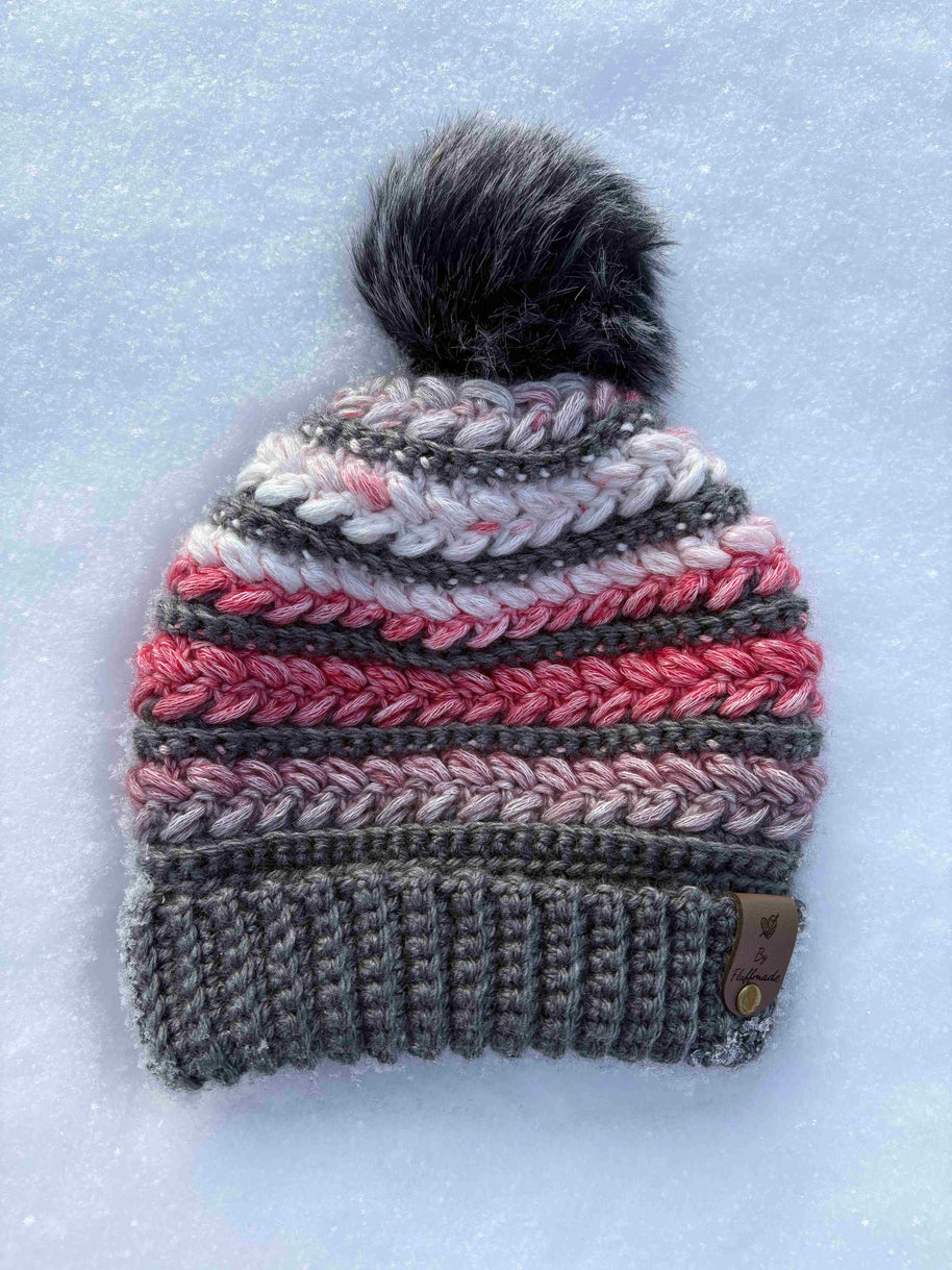 Crocheted beanie with a pom-pom on a snowy background