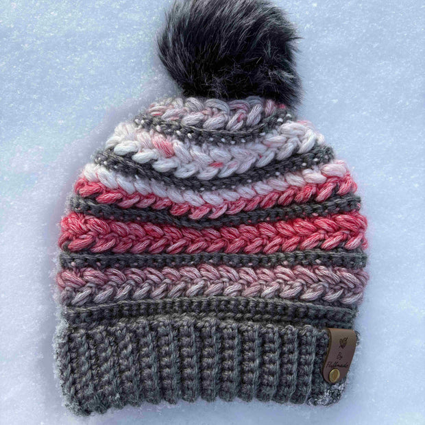 Crocheted beanie with a pom-pom on a snowy background